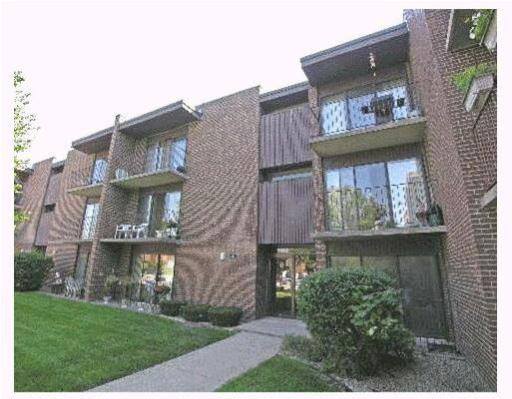 Front view of a multi-story brick apartment building with balconies.