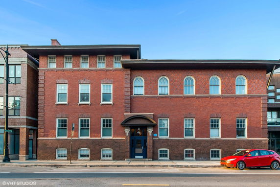 Front view of a brick three-story building with multiple windows and a central entrance.