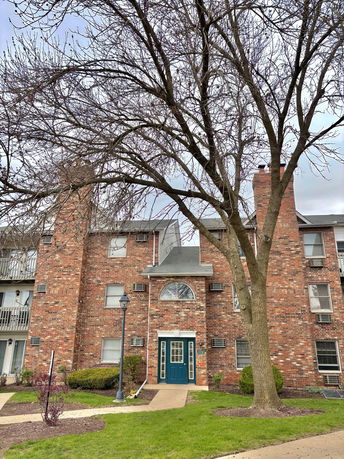 Front view of a multi-story brick apartment building with central entrance.