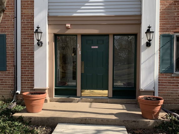 Front view of a building entrance with a green door and sidelights.