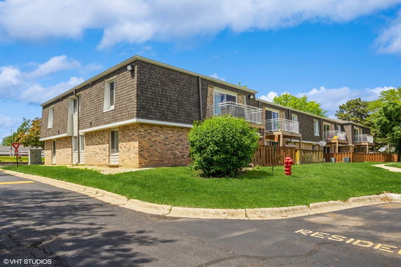 Front view of a two-story residential building with brick and shingle exterior.