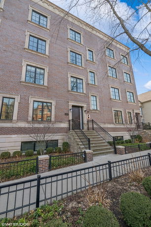 Front view of a four-story brick building with multiple windows and a central entrance with steps.