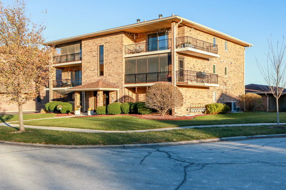 Front view of a three-story brick apartment building with balconies.