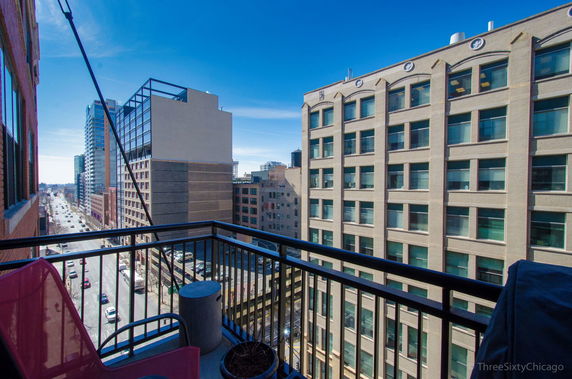 View from a balcony overlooking a city street and surrounding buildings.