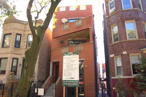 Front view of a multi-story brick building with balconies.