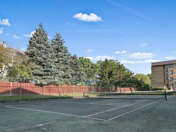 Tennis court outside with a building in the background
