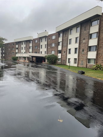 Front view of a multi-story apartment building with brick facade and covered entrance.
