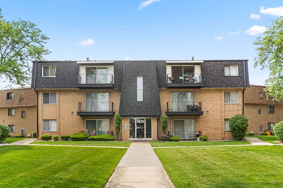 Front view of a multi-story apartment building with balconies and a central entrance.