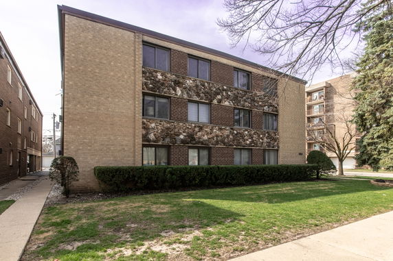 Front view of a three-story apartment building with a brick and stone facade.