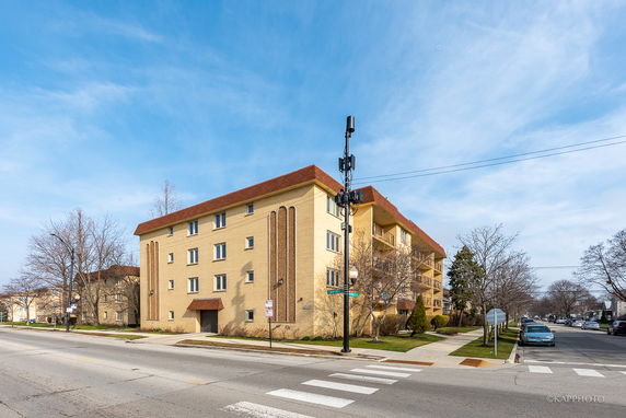 Front view of a multi-story building on a street corner with a brick exterior and a red roof.