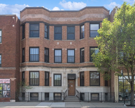 Front view of a three-story brick building with multiple windows.