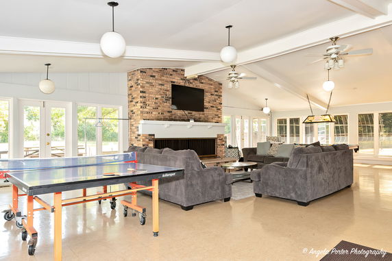 Interior view of a recreation room with sofas, a table tennis setup, and a fireplace.