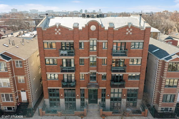 Front view of a multi-story brick building with balconies and large windows.