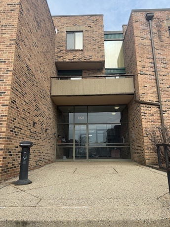 Front view of a brick building entrance with glass doors.