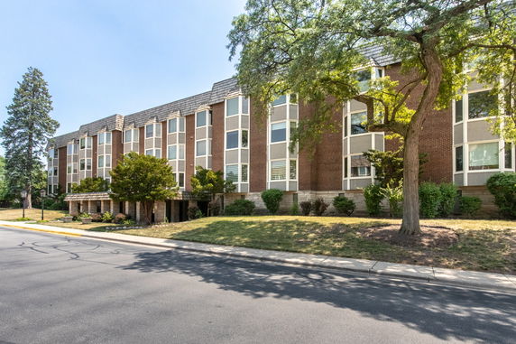 Front view of a three-story brick building with large windows and landscaped surroundings.
