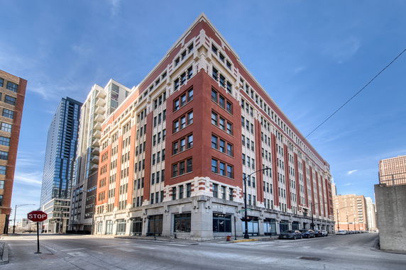 Front view of a large multi-story brick building on a city street corner.