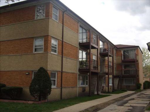 Front view of a multi-story apartment building with brick facade and balconies.