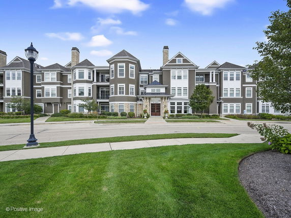 Front view of a multi-story residential building with balconies and gabled roofs.