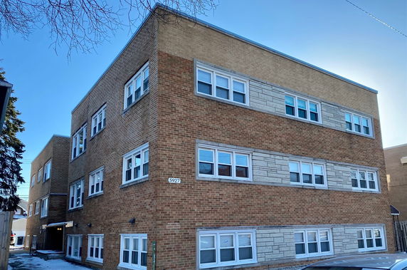 Front view of a three-story brick apartment building with multiple windows.