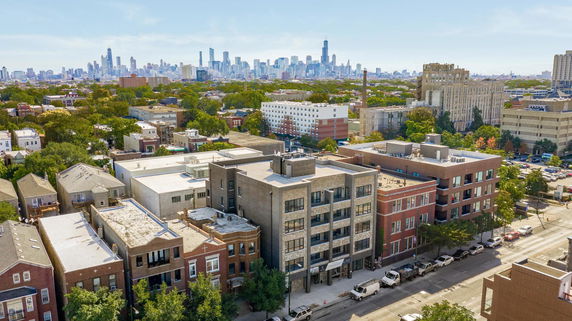 Panoramic view of a cityscape with multiple residential and commercial buildings in the foreground and a city skyline in the background.