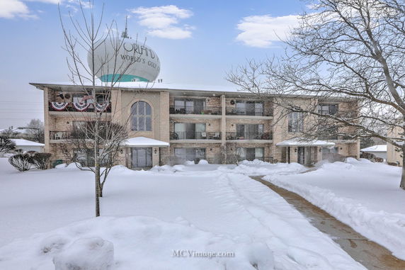 Front view of a three-story apartment building with balconies, covered in snow.