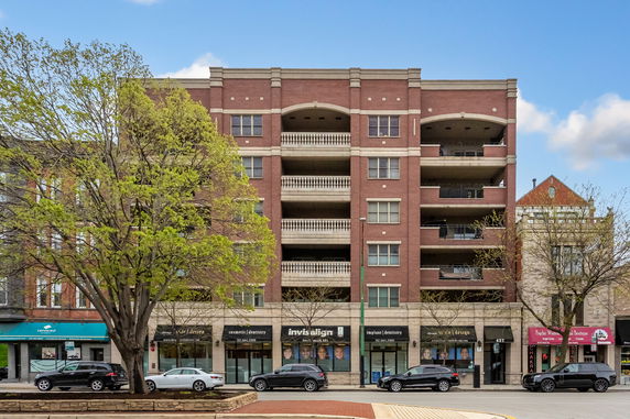 Front view of a multi-story brick building with commercial spaces on the ground floor.