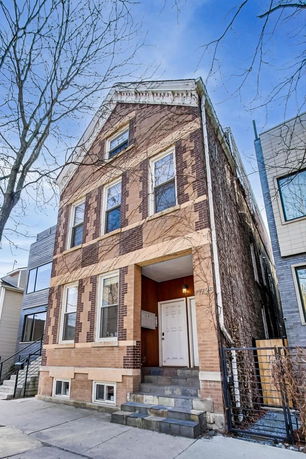 Front view of a multi-story brick building with a small entrance porch and several windows.