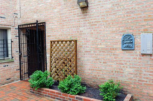 Brick exterior of a building with a metal gate and small garden area.