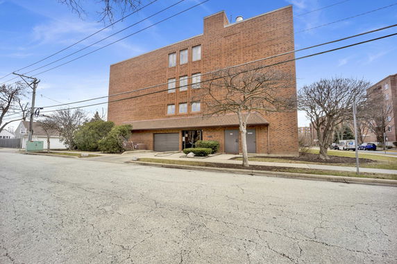 Front view of a multi-story brick building with large windows.