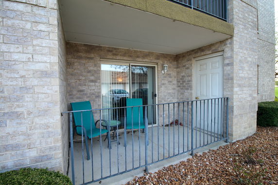 Front view of a residential building with a small patio featuring two chairs and a table.