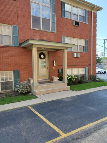 Front view of a multi-story brick building with decorative shutters and a small porch entrance.