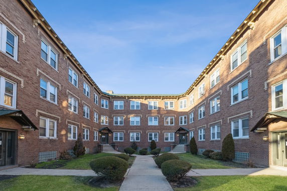 Front view of a multi-story brick apartment building with multiple entrances.