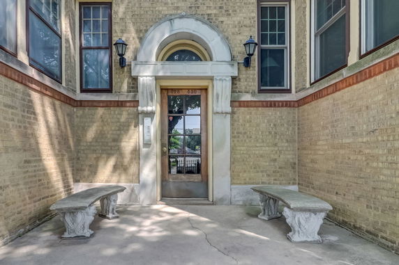 Front view of a building entrance with decorative stone benches.