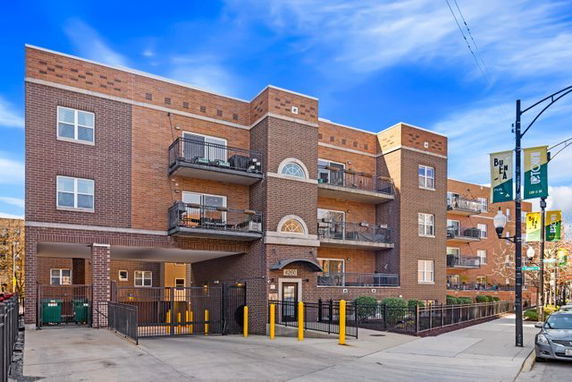 Front view of a multi-story brick apartment building with balconies.
