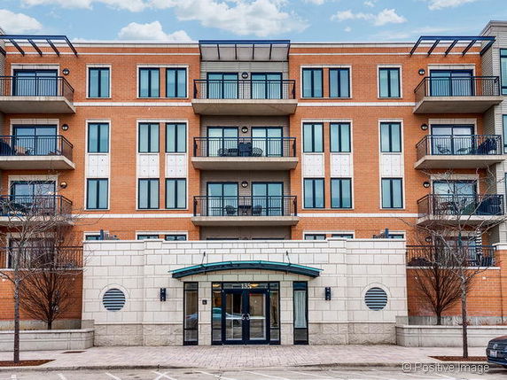Front view of a multi-story brick building with balconies and large windows.