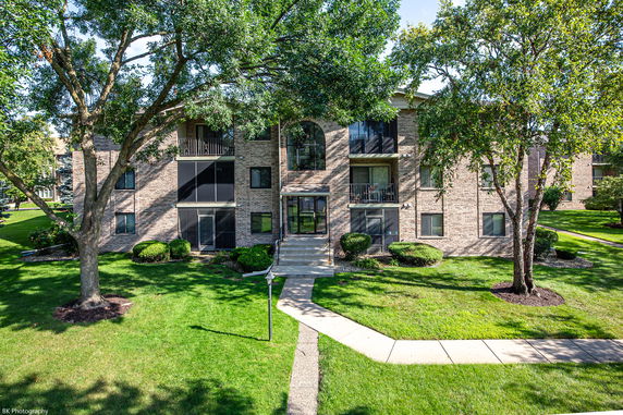 Front view of a two-story brick building with multiple balconies and large windows.