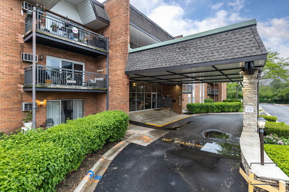 Front view of a multi-story brick building with balconies and a covered entrance.