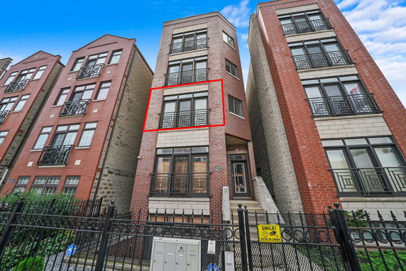 Front view of a multi-story brick apartment building with balconies.