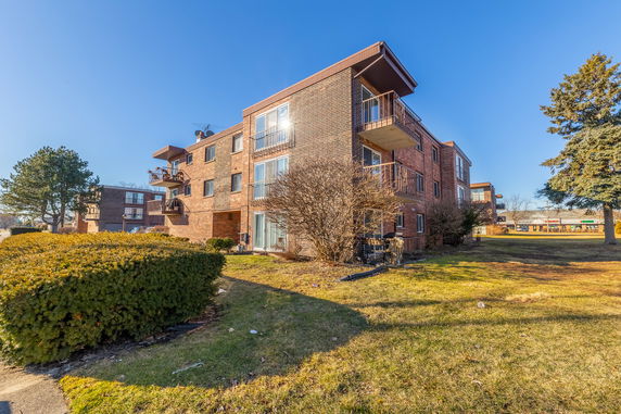 Front view of a multi-story brick apartment building with balconies.