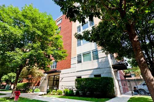 Front view of a multi-story residential building with a brick and concrete exterior.