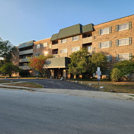 Front view of a multi-story brick apartment building with balconies.