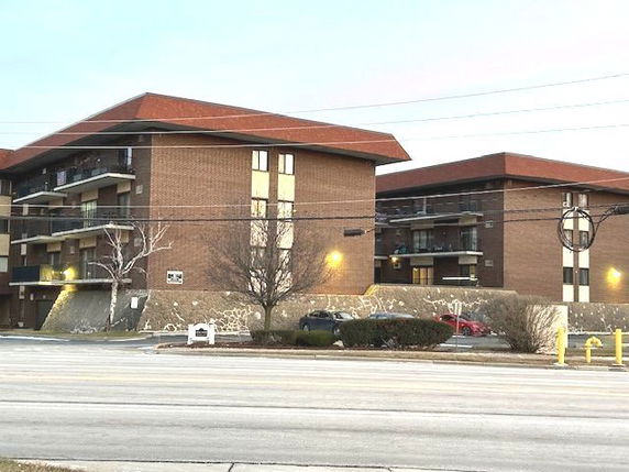 Front view of a multi-story brick apartment building with balconies.