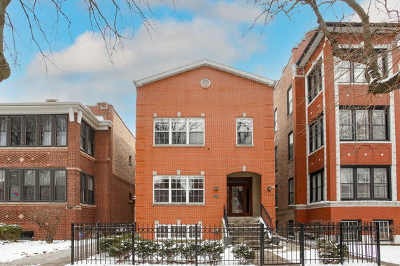 Front view of a two-story brick house with large windows.
