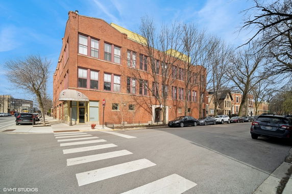 Front view of a three-story brick building on a corner lot.