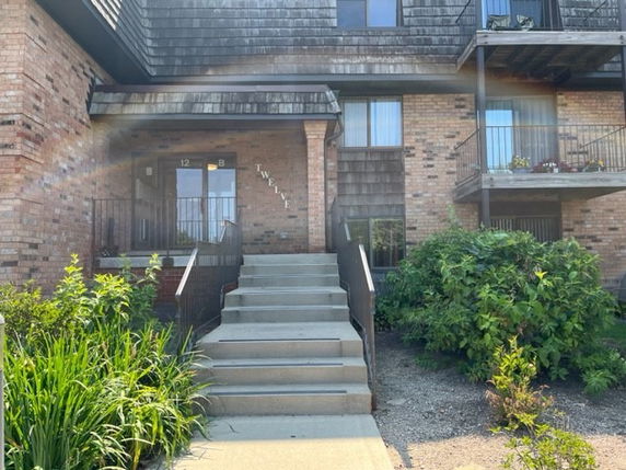 Front view of a multi-story brick building with stairs leading to the entrance.