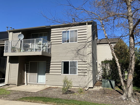 Front view of a two-story house with a balcony and a satellite dish.