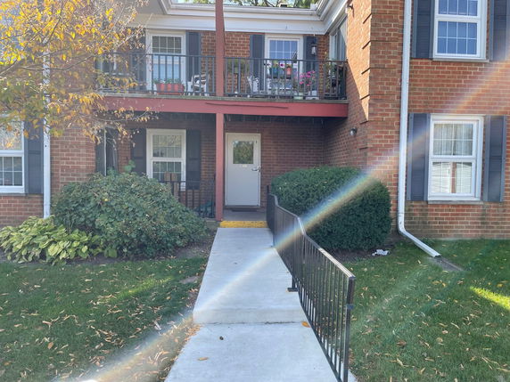 Front view of a two-story brick building with a balcony and pathway.
