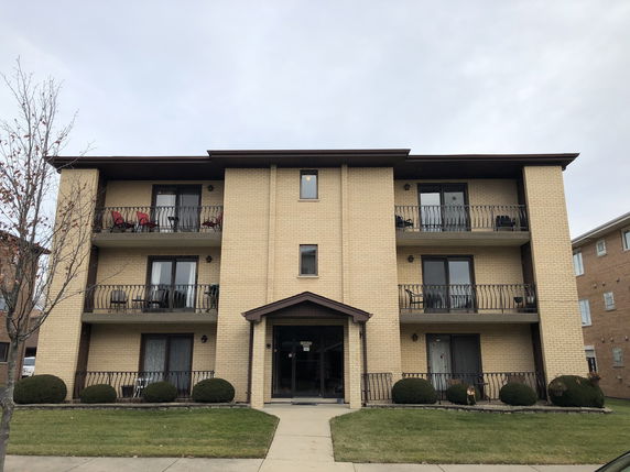 Front view of a three-story apartment building with balconies.