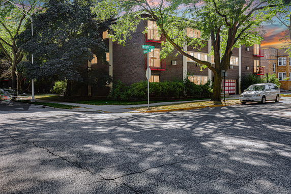 Front view of a multi-story brick apartment building on a street corner.
