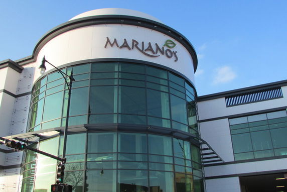 Front view of a modern building with large curved glass windows and a sign reading 'Mariano's'.